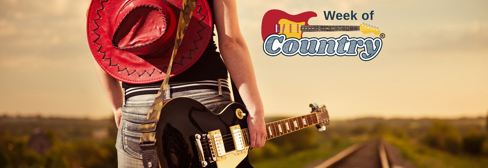 Week Of Country&reg; Music Festival Orlando, Florida.  Woman walking down train tracks with a red cowboy hat and guitar.